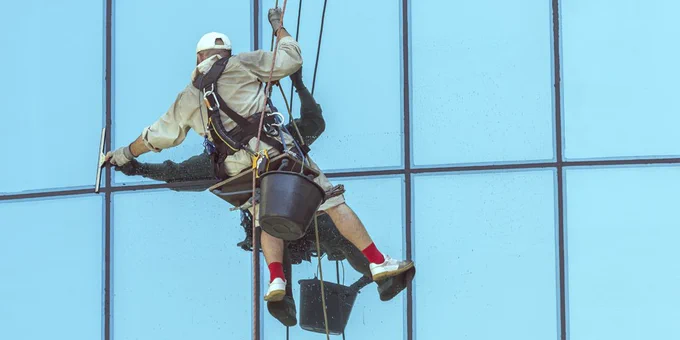 Window cleaner abseiling to clean windows at height