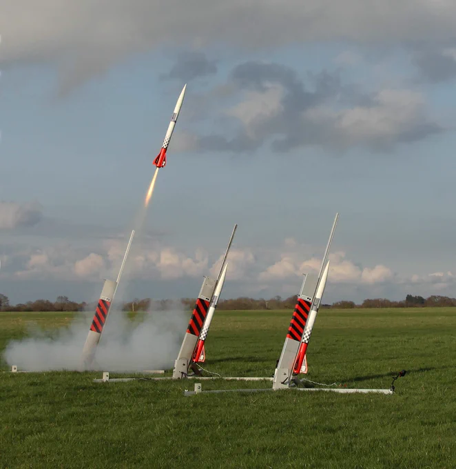Model rockets about to launch in a field.