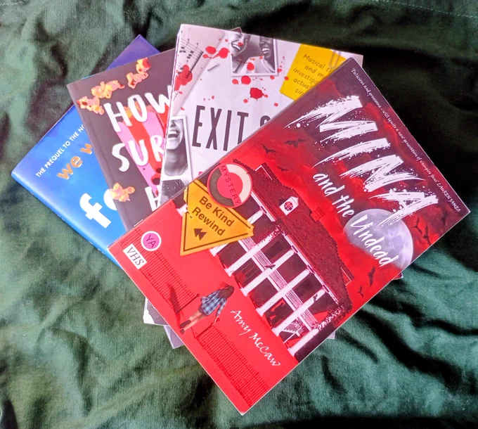 Stack of books featuring Family of Liars, How to Survive a Horror Movie, Exit Stage Death and Mina and the Undead, on a green background 