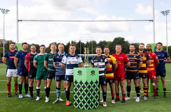Representatives from all 14 Champ Rugby teams stand in a V shape, either side of the Champ Rugby trophy ahead of the 2025/26 season.
