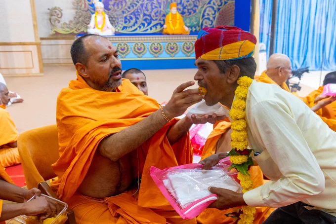 Pujya Yogiprem Swami feeding sweet to a craftsman