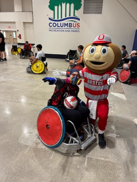 Brutus and one player posing together at the Wheelchair Rugby Tournament