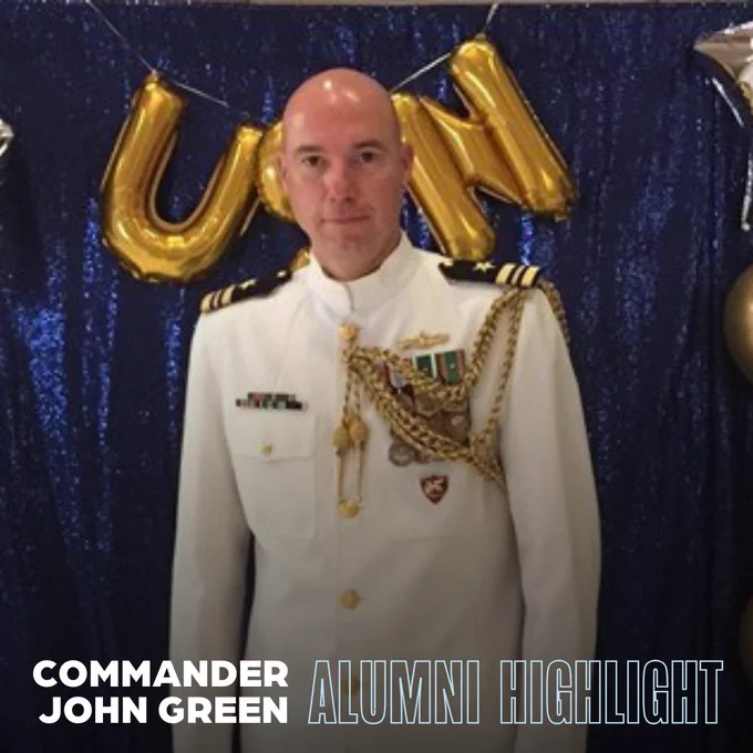 Commander John Green in white naval uniform, standing in front of a backdrop decorated with golden balloons. The graphic says "Alumni Highlight. Commander John Green."