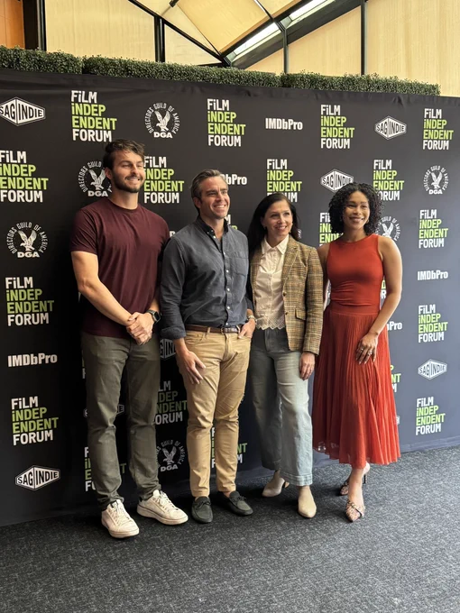 Two men and two women stand in front of a black step and repeat with “Film Independent Forum” written in green and white.