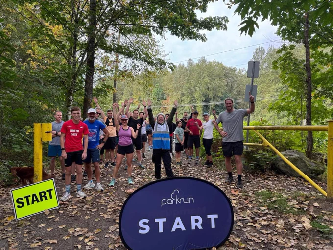 A group of parkrunners with their arms up at the start line.