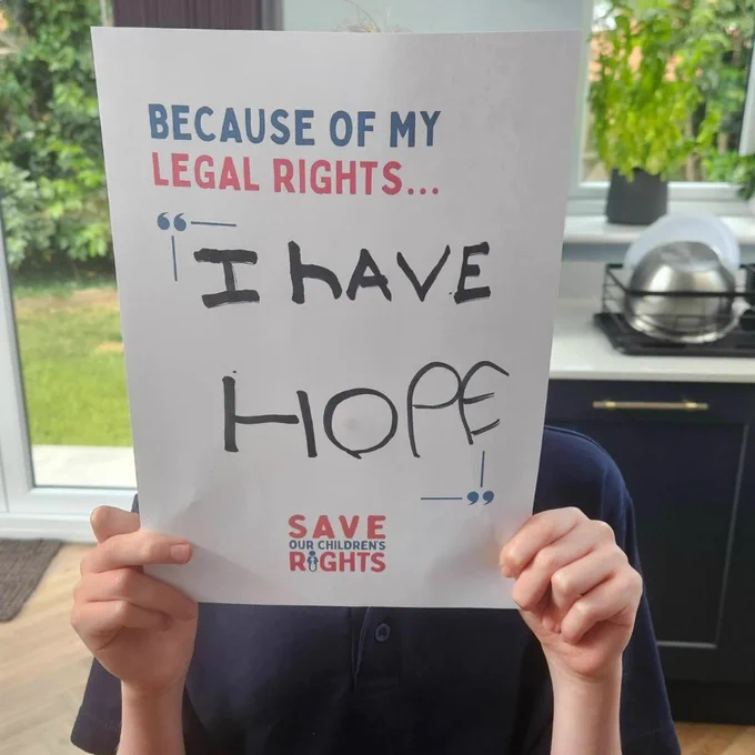 A photo of a child holding a sign that says 'Because of my legal rights...I have hope'