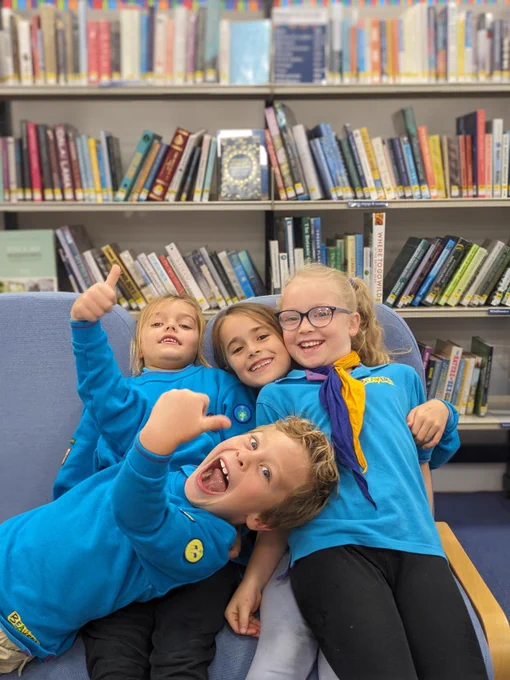 Photo of 4 children from a Beavers group posing in front of bookshelves at Godalming Library in Surrey.