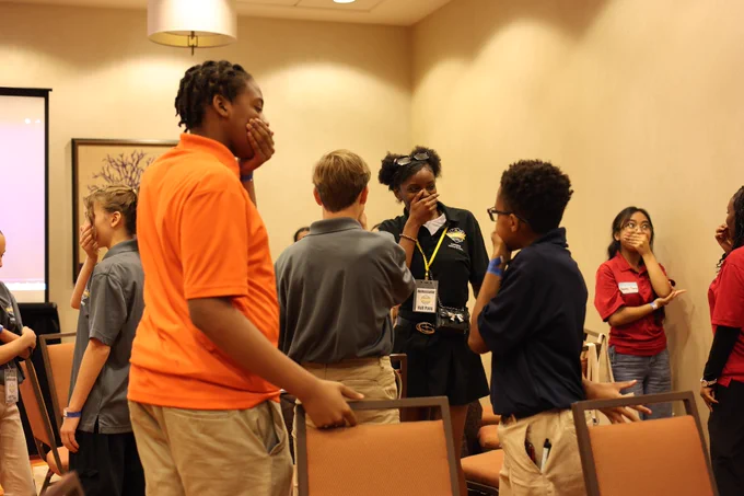 Students walk around covering their mouths during an activity at the Explore Ambassadors conference.
