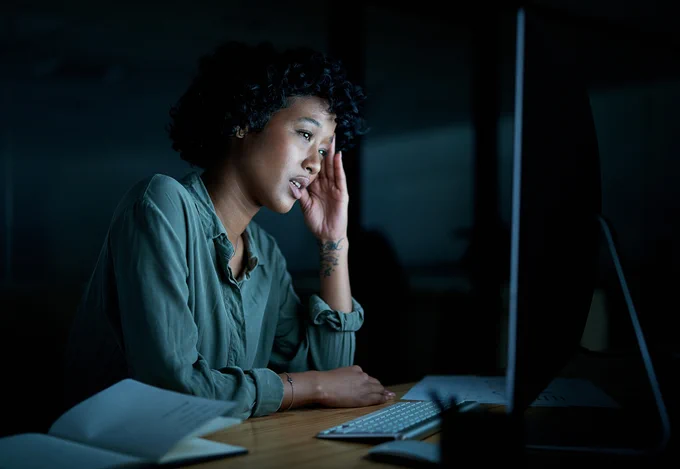 A woman working at a computer in a dark room