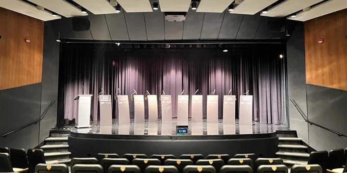 Empty debate stage with multiple podiums set up at the Stanley A. Milner Library's Muttart Theatre, awaiting speakers.