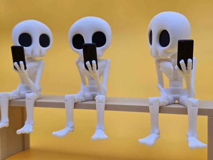 Three 3D printed Skeleton Hazy figures sit in a row on a beige bench, each holding a small black phone. The identical poses and hollow eyes make a playful commentary on screen addiction.