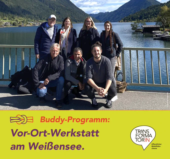 Abbildung: Eine Gruppe Menschen steht auf einer Brücke und lächelt in die Kamera. Dahinter ein See, eingerahmt von Bergen.  Es scheint die Sonne, am Himmel vereinzelt Wolken. Die dargestellten Personen: Hintere Reihe: Daniele Marano, Karoline Turnschek, Raffaela Lackner, Lisi Kuster Vorne: Wolfgang Voglauer, Thomas Michor, Martin Aufhauser

Überschrift: Vor-Ort-Werkstatt am Weißensee.
Subline: Buddy-Programm
Logo: Transformator:in, Logozusatz: öffentlicher Mobilitätsräume
