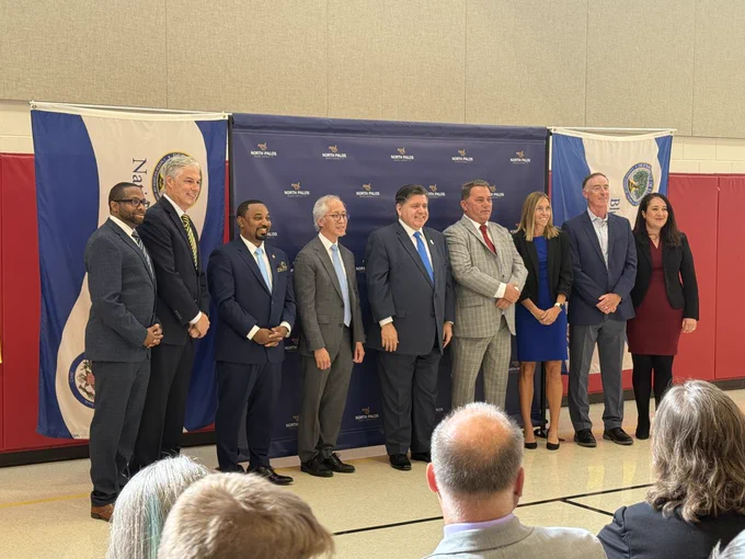 Press conference attendees pose for a picture in gymnasium. 