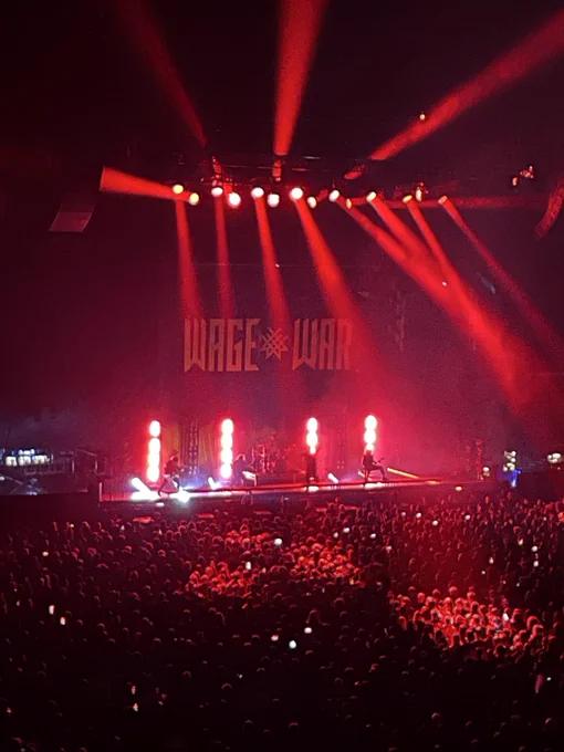 Image of inside co op music venue, scene of people on a floor facing a stage where the band wage war perform.