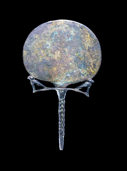 Ancient bronze mirror with a round reflective surface and a braided handle, featuring a simple, elegant design against a black background.