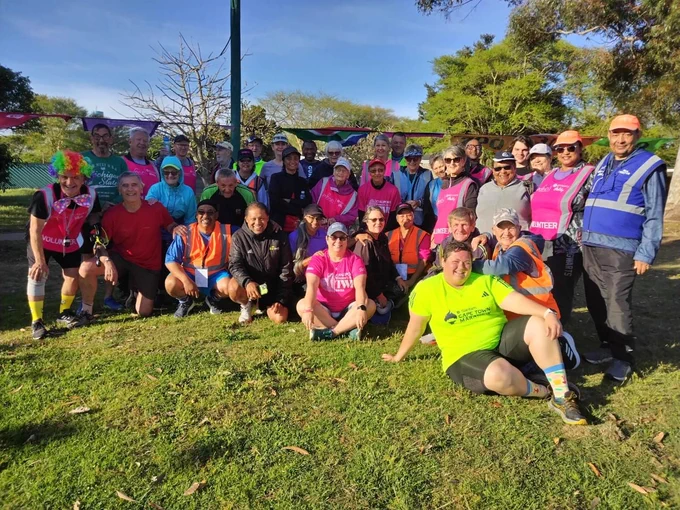 A group of parkrunners in bright colours sat on the grass.