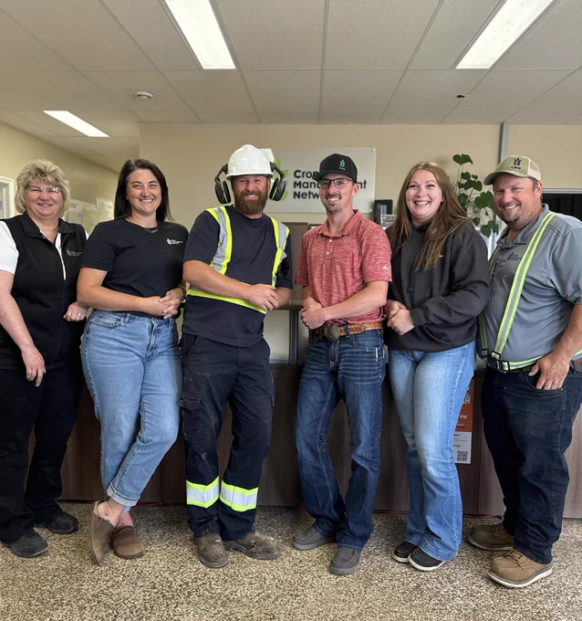 Group of six people, one in a hard hat, standing in the Edberg, AB CMN office.