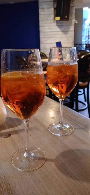 On the table are two glasses of aperol sprizt 