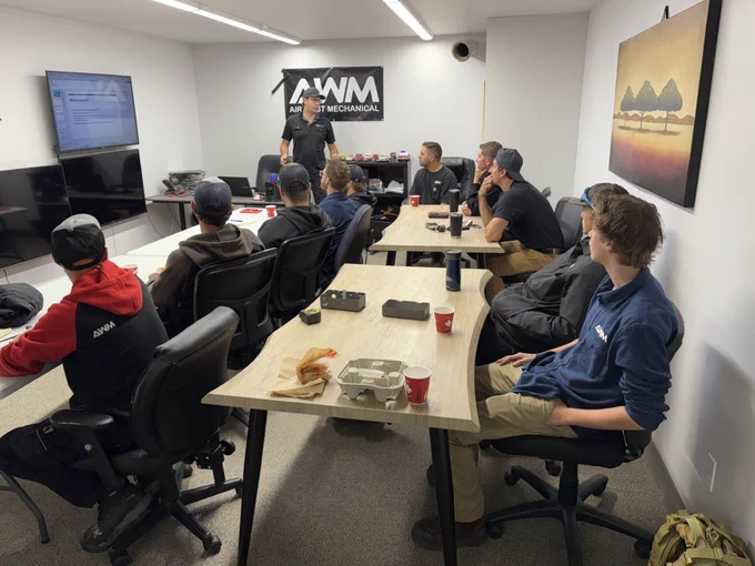 A professional team meeting in Calgary for Air West Mechanical. Team members are gathered around a conference table, discussing plans and strategies. Laptops, notes, and coffee cups are on the table, showing collaboration and teamwork in action. The atmosphere is energetic and focused, highlighting the company’s commitment to excellence and innovation in mechanical solutions. 