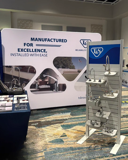 Trade show booth for T&S Brass featuring displays of various plumbing fixtures and branded banners emphasizing reliability and ease of installation.