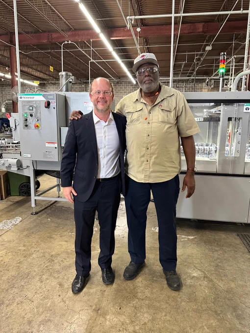 Acting Chairman Peter Feldman stands beside a Lighthouse for the Blind employee on the factory floor in St. Louis, Missouri, highlighting the skilled workforce behind the facility’s aerosol production lines.