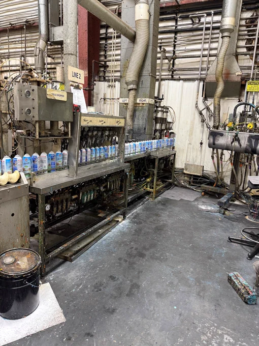 A row of aerosol cans moves down the Lighthouse for the Blind production line in St. Louis, Missouri, illustrating the facility’s large-scale, hands-on manufacturing process.