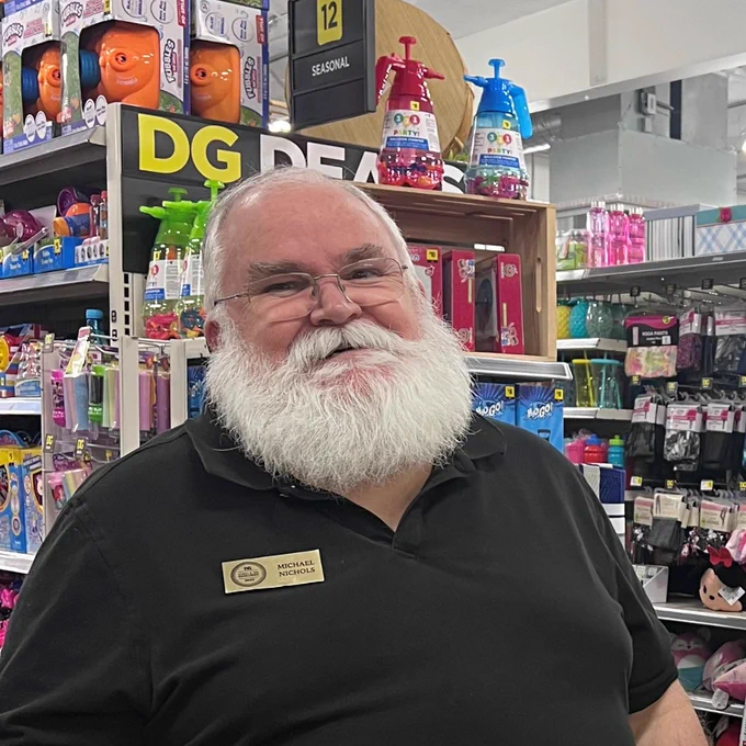 Employee standing in store aisle.