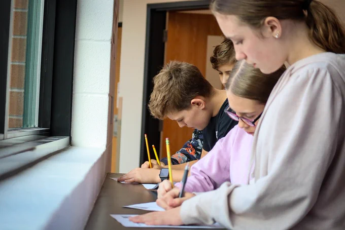 Kids at a table top writing on paper