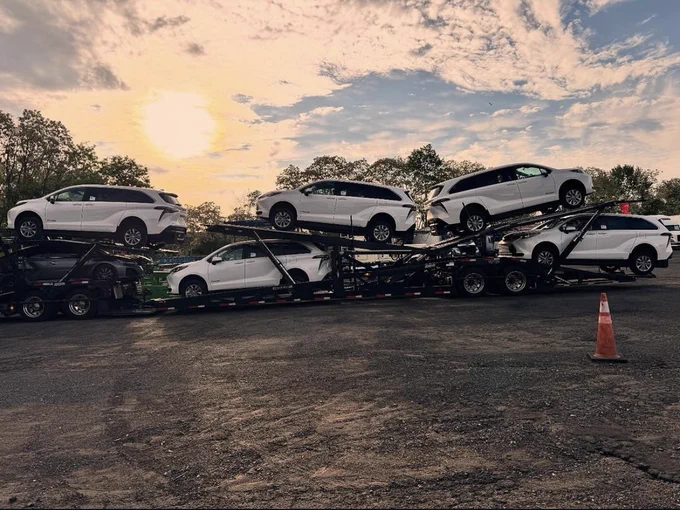 White Wheelchair vans on a car hauler. In the background, the sun and clouds are visible.