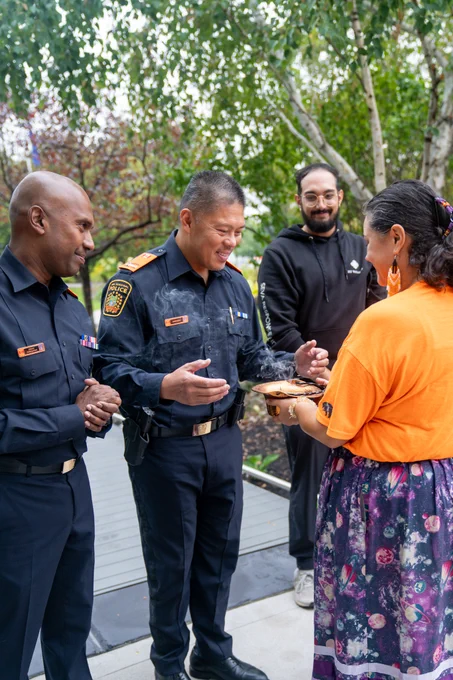 Chief of Peel Police and Deputy Chief interacting with individual carrying traditional bowl as a part of ceremonial practice.