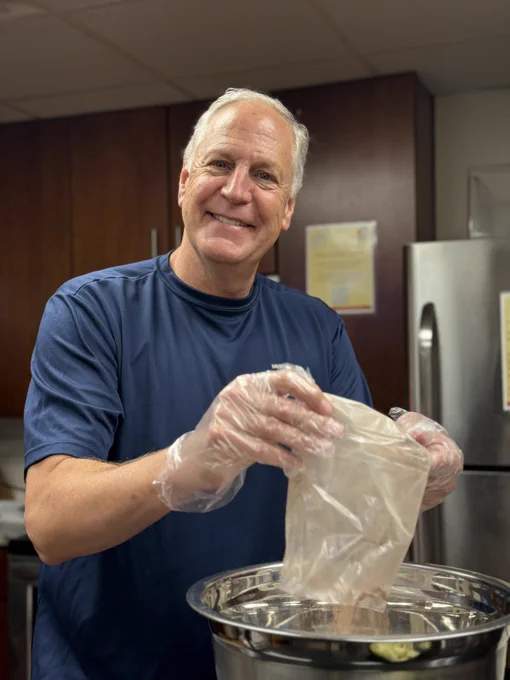 A smiling volunteer makes a meal in the main kitchen of The Doorways