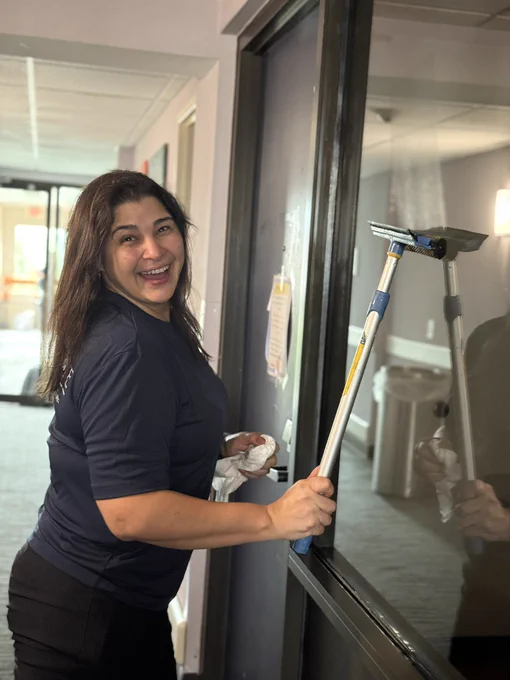 A smiling volunteer cleans windows and balconies at The Doorways