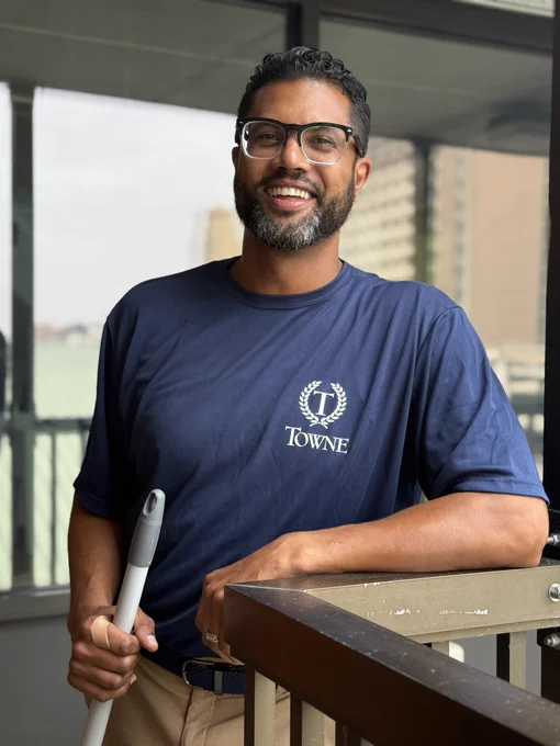 A smiling volunteer cleans windows and balconies at The Doorways