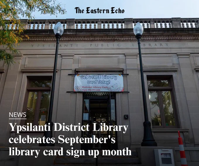 Exterior of the Michigan Avenue Ypsilanti District Library branch, a stone building with large windows and two tall lampposts flanking the entrance. A banner above the doorway reads, “Get a FREE Library Card Today! National Library Card Sign-Up Month.” The image caption reads, “News. Ypsilanti District Library celebrates September's library card sign up month.”