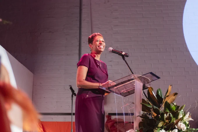 Speaker Adrienne Adams smiles in front of a podium at a gala at the Chocolate Factory Theater.