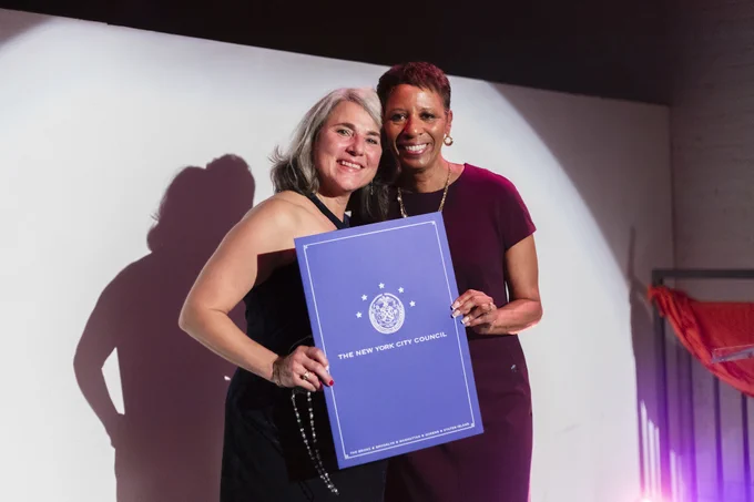 Speaker Adrienne Adams holds an award with Chocolate Factory Theater former executive director Sheila Lewandowski.