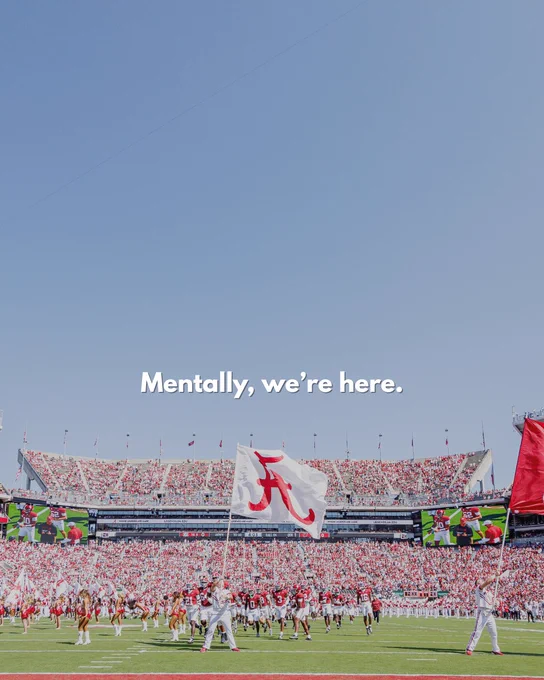 An image of a crowded Bryant-Denny Stadium during a daytime sports event with spectators and players on the field, featuring a flag with a horse emblem waving prominently. The words "Mentally, we're here." are seen on the screen.