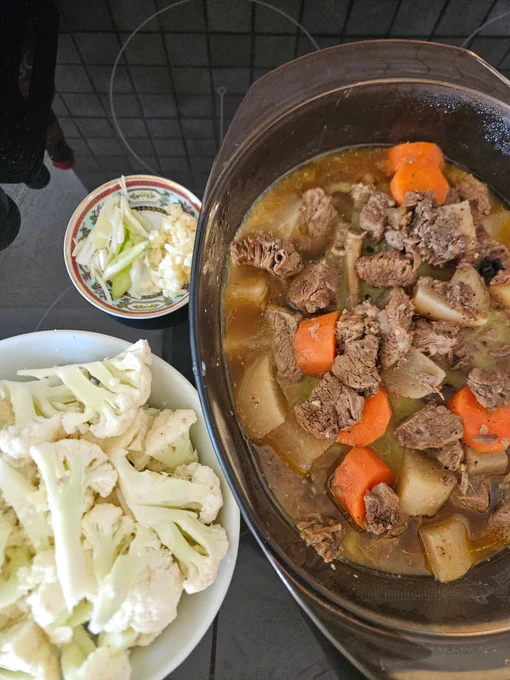Ingredients clockwise from left of a bowl of cauliflower pieces, a small dish with sliced spring onion & minced garlic, a casserole dish with the slowcooked beef brisket, daikon, carrot, lemongrass.
