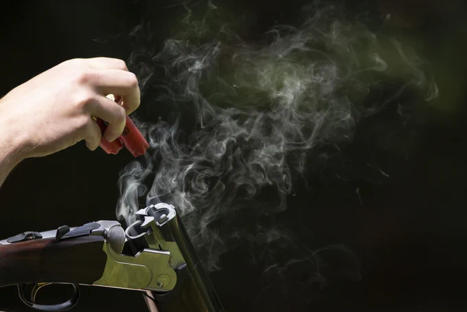 Hand nimmt zwei Hülsen aus einer rauchenden Flinte. (Quelle: Wildgeflüster/DJV)