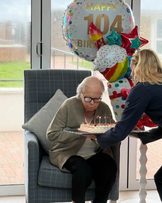 Nancy smiling and blowing out candles on her birthday cake.
