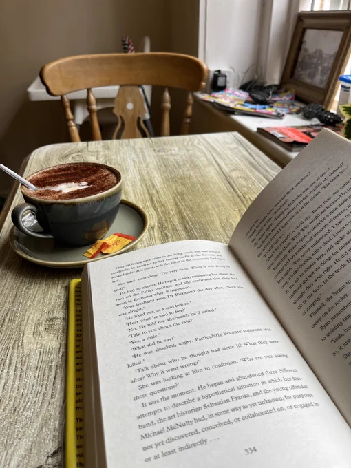 Photo of an open book and a cup of coffee on a table in a cafe