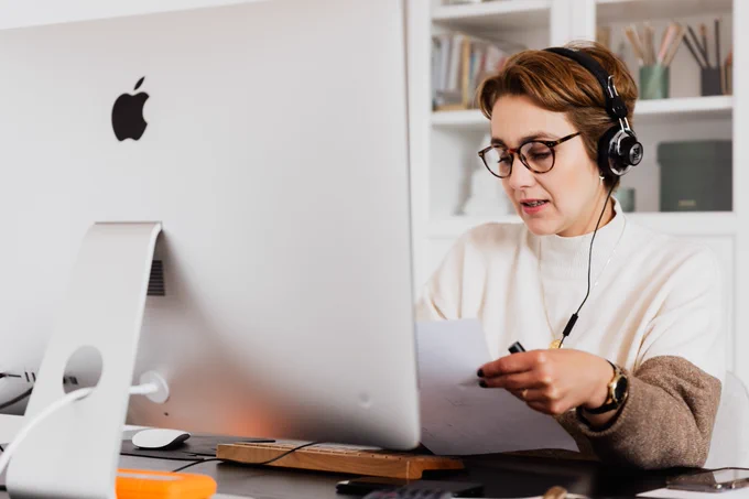 Person with headphones on in front of a computer screen