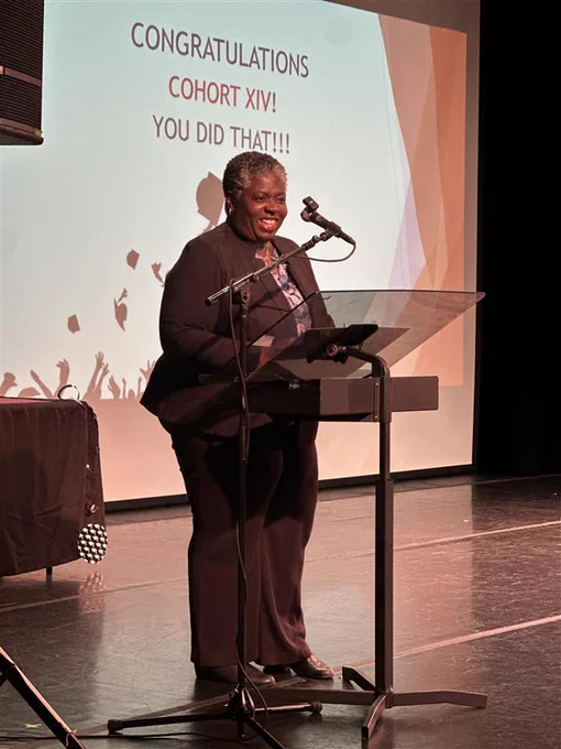 S B S Commissioner Dynishal Gross speaking on stage to the Healthcare Finance & Operations program graduates at the graduation ceremony