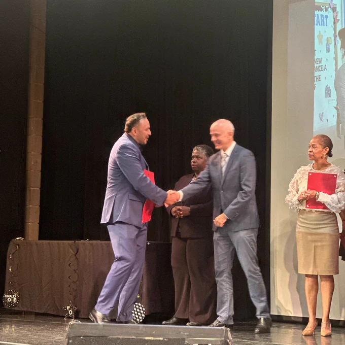 Alexander Padilla shaking a man's hand on stage at the Healthcare Finance & Operations program graduation