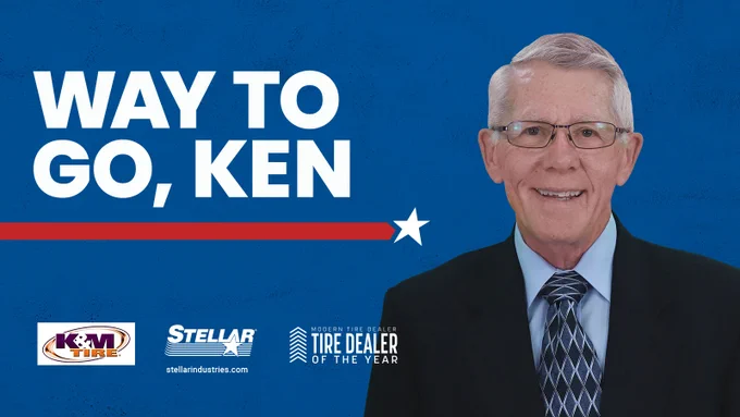 Banner featuring the text 'Way to Go, Ken' alongside a smiling individual in a suit, with logos of K&M Tire and Stellar Industries, and a caption stating 'Tire Dealer of the Year.'