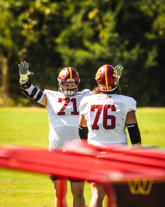 Photo of Sam Cosmi and Andrew Wylie at practice. Wylie is pretending to bow towards Cosmi. 