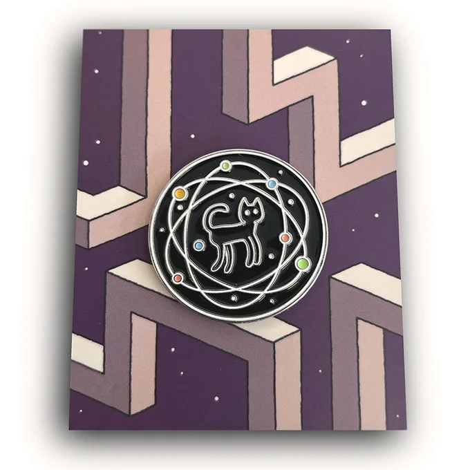 A pin badge depicting a black cat floating in a black void orbited by colourful particles.