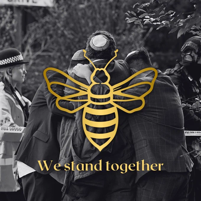 Three Jewish people standing in a huddle with a gold bee symbol and the words We Stand Together. A police officer is in the background.