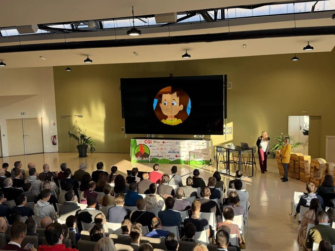 La salle comble au fond de la salle une slide.
Sur la droite estelle et emilie debout.