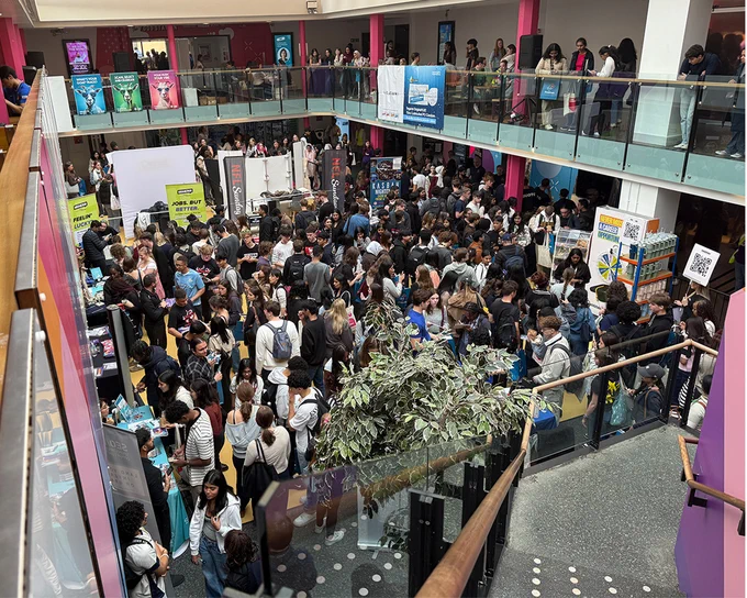 The Warwick Welcome Fair inside the student union atrium with crowds of students exploring booths and displays on two levels.